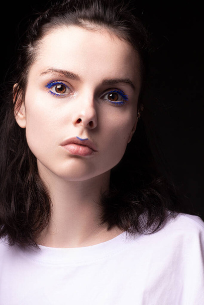 fashionable woman with blue eye makeup and check mark on lips, portrait close-up, black background - Фото, зображення