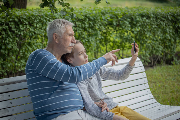 portrait of a boy and grandfather, happy, cheerful grandfather and grandson with smartphone taking selfie at summer park, Leisure concept, school summer holidays - Fotoğraf, Görsel