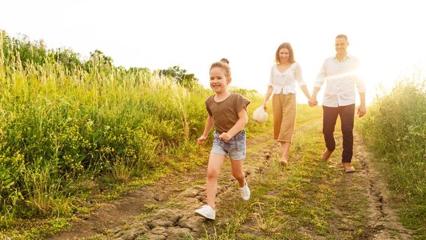 Szczęśliwi rodzice i dziecko spacerujące razem na świeżym powietrzu w lecie - Zdjęcie, obraz