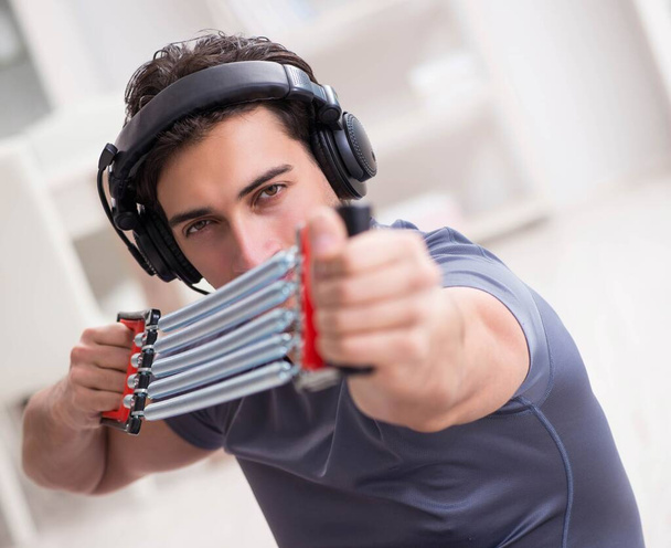 Άνθρωπος που κάνει αθλήματα με μπάντα αντίστασης και ακούει μουσική - Φωτογραφία, εικόνα