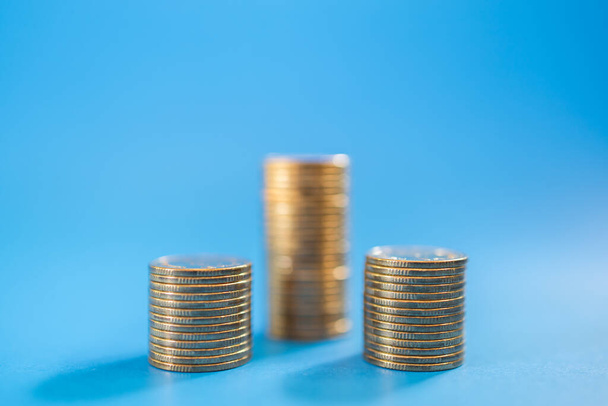 Geld, zaken en risico concept. Close-up van stapel munten op blauwe achtergrond met kopieerruimte. - Foto, afbeelding