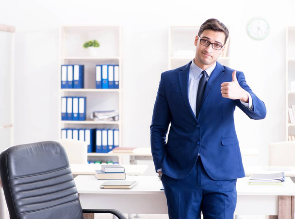 Молодой привлекательный бизнесмен, работающий в офисе за столом - Фото, изображение