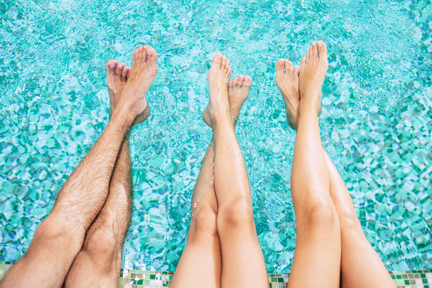 Human legs in the pool. Vacation at a summer hotel. Legs on water background. Family in the swimming pool - 写真・画像