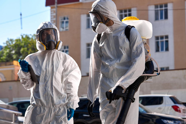 specialists in hazmat suits cleaning disinfecting coronavirus cells epidemic, pandemic health risk - Foto, imagen