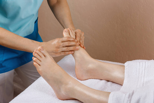 Een vrouw kwam naar een professional voor voetmassage. Close-up van vrouwelijke benen. Professionele masseur doet voetmassage - Foto, afbeelding