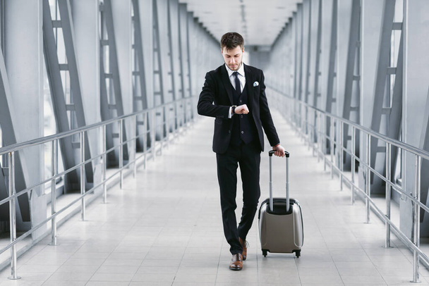 Adult business man standing in airport with suitcase - Photo, Image