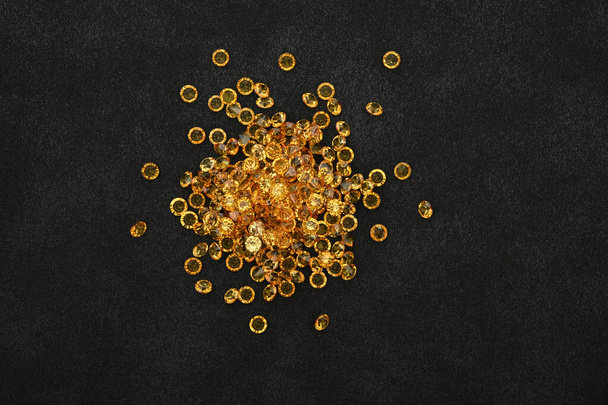 Közelkép halom arany sárga strasszos kristályok felett fekete bőr háttér, emelkedett felülnézet, közvetlenül felette - Fotó, kép