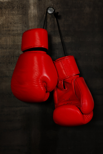 Close up pair of red leather boxing gloves hanging over black wall with copy space - Foto, Imagem