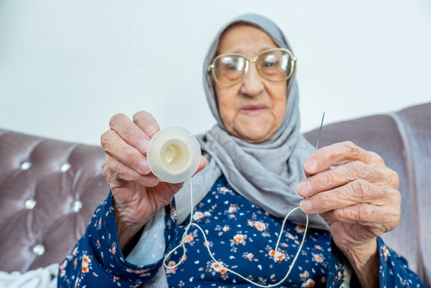 Arabic muslim old woman inserting thread in needle - Photo, Image