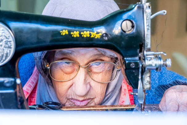 Αραβική muslim ηλικιωμένη γυναίκα χρησιμοποιώντας παλιά ραπτομηχανή - Φωτογραφία, εικόνα