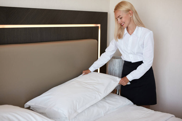 гарна покоївка готує ліжко для гостей
 - Фото, зображення