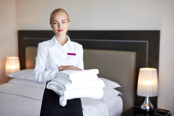 attractive maid with towels in hands - Foto, Imagen