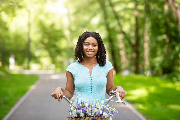Портрет красивої чорної дівчини, яка збирається кататися на велосипеді в парку в сонячний день
 - Фото, зображення