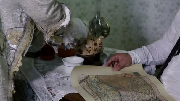 άνθρωπος να πάρει το φλιτζάνι του τσαγιού και κοιτάζοντας ένα παλιό χάρτη - Πλάνα, βίντεο