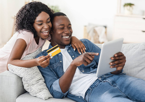 Счастливая супружеская пара из Африки покупает вещи в интернете, используя цифровой планшет
 - Фото, изображение