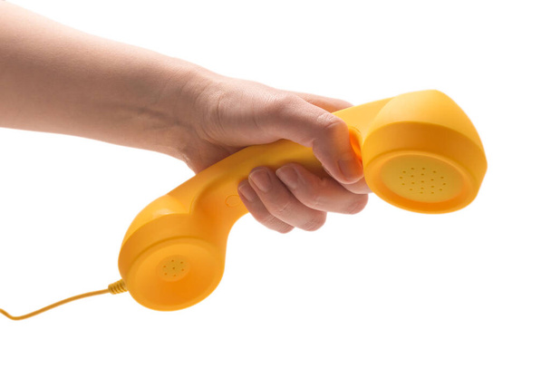 Żółty telefon w ręce kobiety odizolowany na biało. Przestrzeń kopiowania. - Zdjęcie, obraz