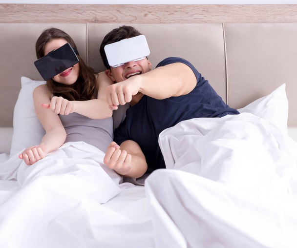 Femme et mari avec des lunettes de réalité virtuelle dans le lit - Photo, image