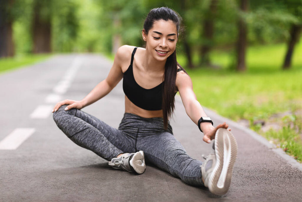 Aziatisch meisje stretching been spieren na het lopen in park, zitten op pad - Foto, afbeelding