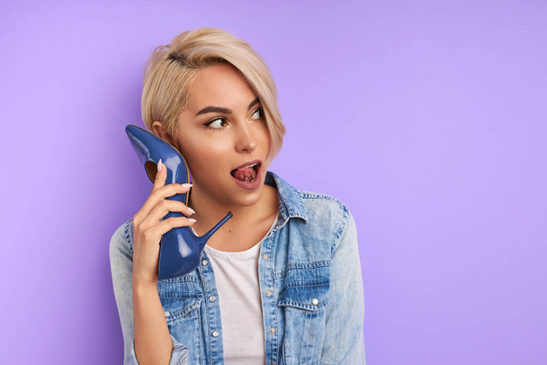 cute adorable woman hold blue shoes as phone - Foto, afbeelding