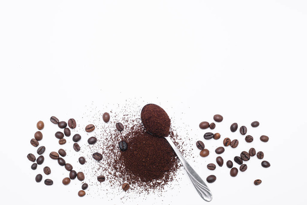Grounded coffee in a spoon surrounded with beans isolated - Foto, Imagen