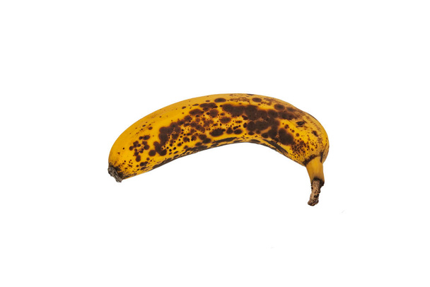 Η κίτρινη μπανάνα είναι υπερώριμη και έχει καφέ κηλίδες πάνω της. Η μπανάνα απομονώνεται σε λευκό φόντο. - Φωτογραφία, εικόνα