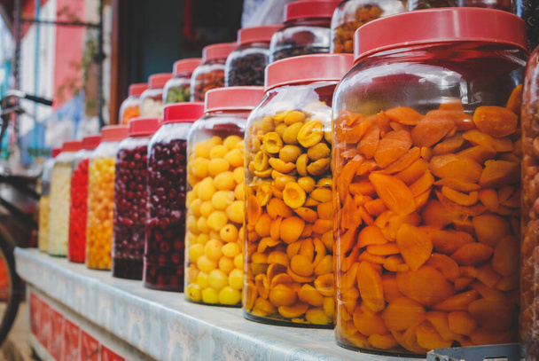Pickled Fruits in glass jar arranging in the shop shelf for sale with outdoor lighting. - Fotó, kép