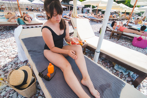 donna mettere crema solare lozione sulle gambe. tempo in spiaggia - Foto, immagini