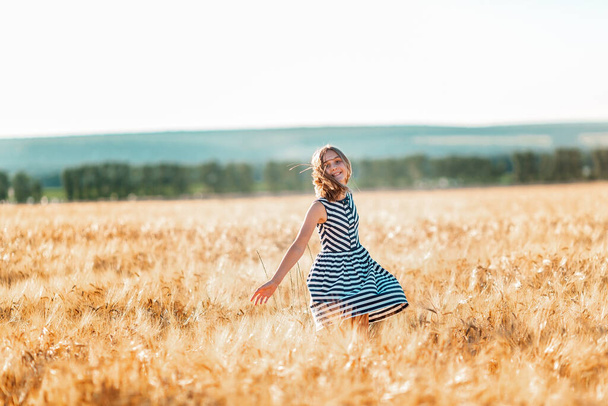 szczęśliwy nastolatek piękne dziewczyna działa w dół złoty pszenicy pole na zachód słońca - Zdjęcie, obraz