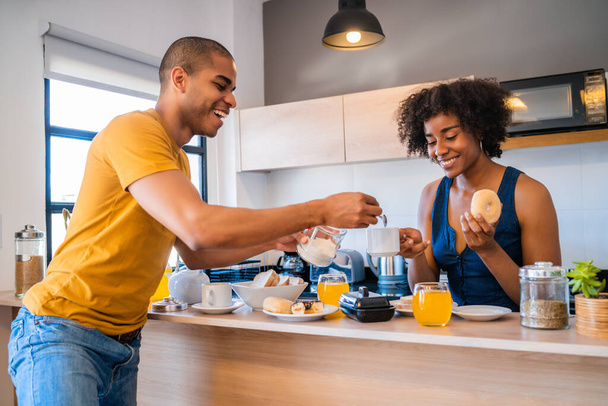 Portrait of happy young couple having breakfast together at home. Relationship and lifestyle concept. - Фото, изображение