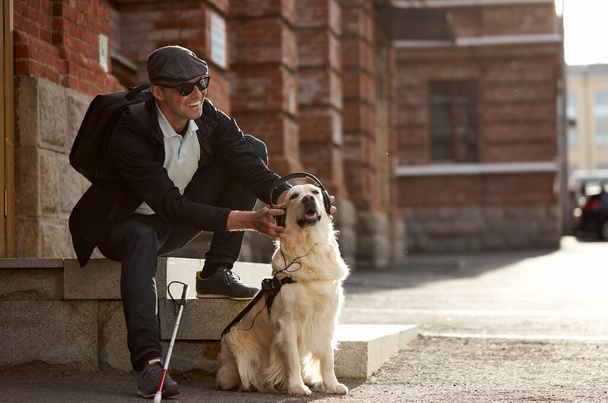 happy blind male entertains his guide dog - Foto, afbeelding