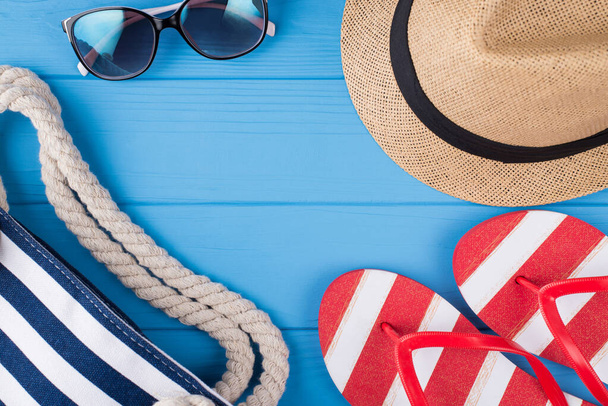 Summer vacation concept. Top above overhead view photo of bag sunglasses hat and flipflops isolated on blue wooden background - Photo, Image