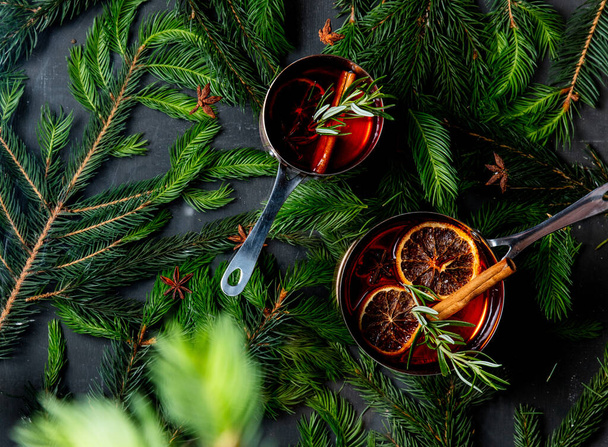 Hot gluhwein drink in a pot with Christmas tree branches around. Above view  - Foto, imagen