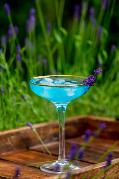 cocktail bleu avec glace et lavande sur un plateau dans un jardin - Photo, image