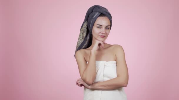 Woman with towel on head looking at camera, smiling, isolated on pink background - Video