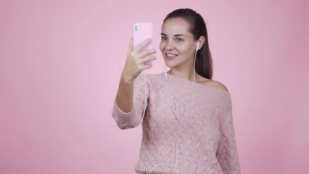 Girl blogger makes video story using mobile phone isolated on pink background - Felvétel, videó