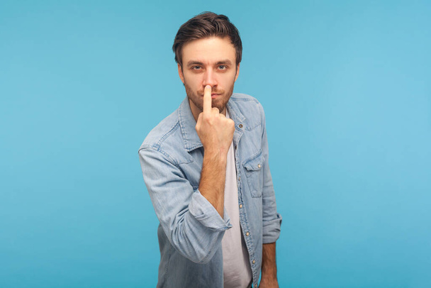 Don't lie to me! Portrait of man in worker denim shirt touching nose, showing liar gesture, angry about falsehood, outright deception, fake news. indoor studio shot isolated on blue background - Foto, immagini