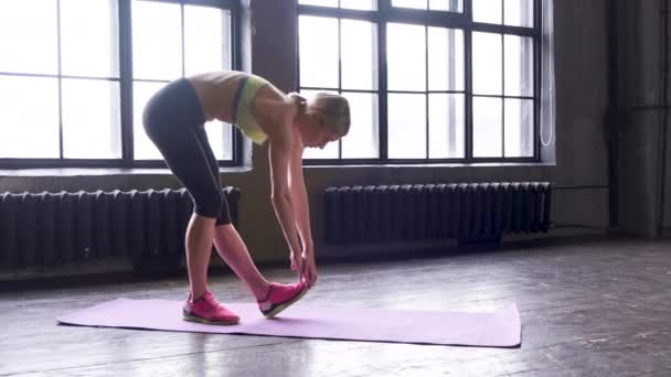 Egy fiatal szőke nő nyújtózkodik egy nagy stúdióban nagy ablakokkal Sport diéta Slim Body Concept - Felvétel, videó