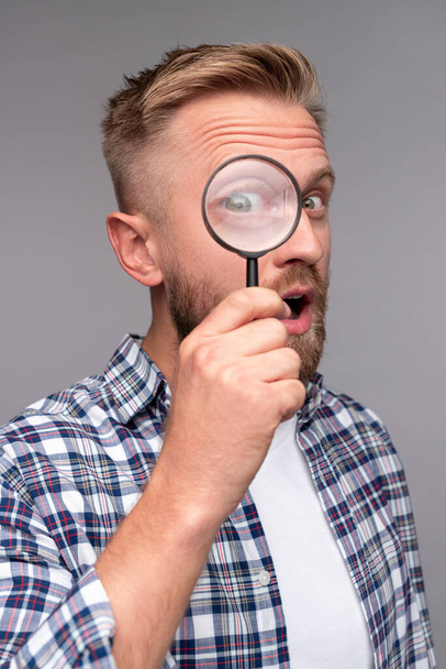 Curious man with magnifying glass looking at camera - Photo, Image