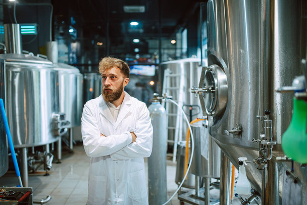  Porträt eines professionellen kaukasischen gutaussehenden Technologen in weißer Uniform, der in einer Pharma- oder Lebensmittelfabrik steht - Produktionsanlage - Foto, Bild