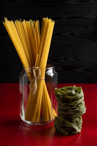 Espaguetis en un frasco de vidrio con pasta verde alrededor
 - Foto, Imagen