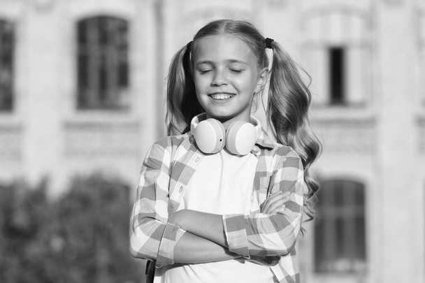 cheerful music lover. small girl wear checkered shirt. child with headset at sunset. kid spring and summer fashion. happy childhood. e-learning with ebook. modern technology - Fotoğraf, Görsel
