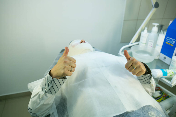 Una visita a una esteticista. El doctor está arreglando la máscara. El procedimiento es carboxiterapia. - Foto, Imagen