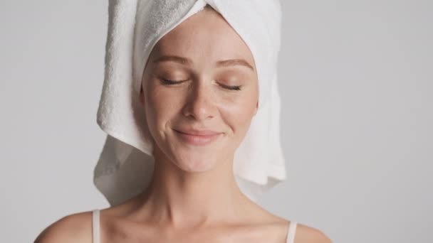 Ritratto di bella ragazza con asciugamano sulla testa sensualmente guardando in macchina fotografica su sfondo grigio. Espressione facciale - Filmati, video