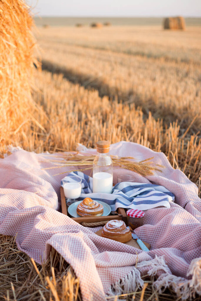 picnic in a wheat field near Round Bales. milk and cinnamon roll - Photo, Image