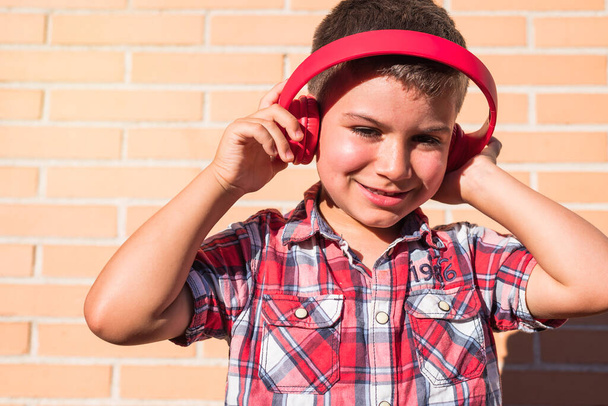 portré gyerek zenét hallgat fejhallgató téglafalon - Fotó, kép