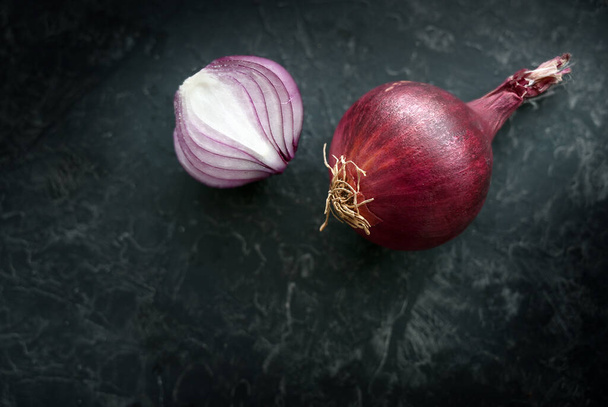 Red onion whole and halved, healthy and spicy vegetable on a dark slate background with copy space, selected focus - Foto, Bild