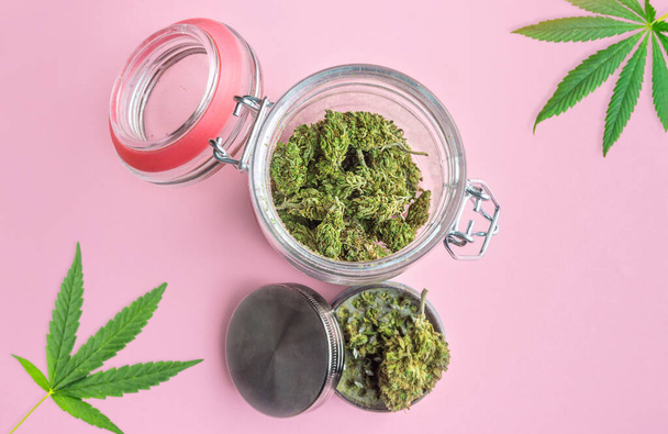 Kotimainen marihuana muuraripurkissa silmut ja hiomakone eristetty pastelli vaaleanpunainen, Medical Cannabis käsite - Valokuva, kuva