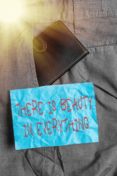 Text sign showing There Is Beauty In Everything. Conceptual photo the world is an endless array of magic Small little wallet inside man trousers front pocket near notation paper. - Foto, Imagen