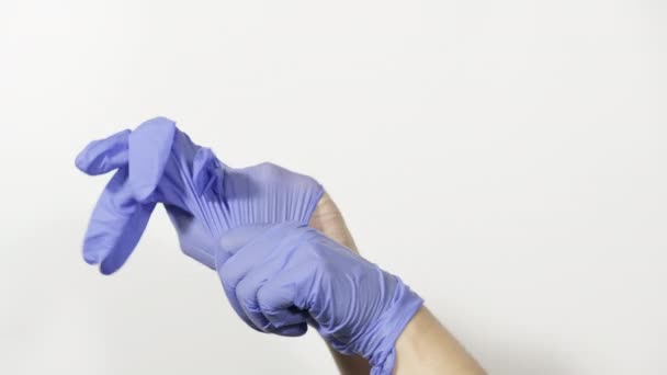 Процесс надевания на руки голубых латексных стерильных перчаток, концепция безопасности и защиты от вирусов во время эпидемии и пандемии, белый фон - Кадры, видео