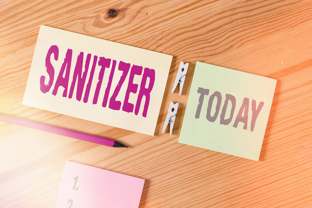 Conceptual hand writing showing Sanitizer. Business photo text liquid or gel generally used to decrease infectious agents Colored crumpled papers wooden floor background clothespin. - Фото, изображение